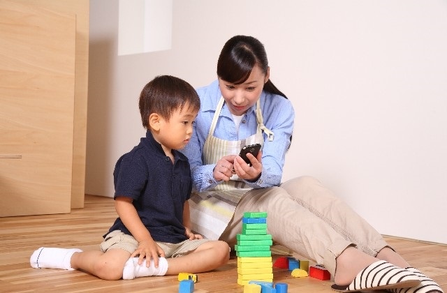 女性がもつスマホを興味津々に見つめる男の子