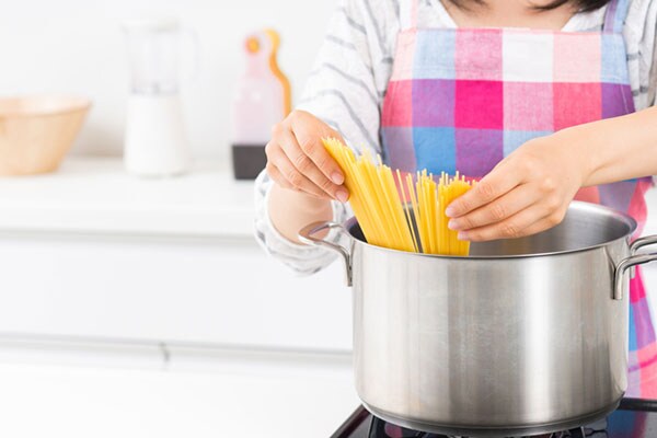 スパゲッティを茹でる女性