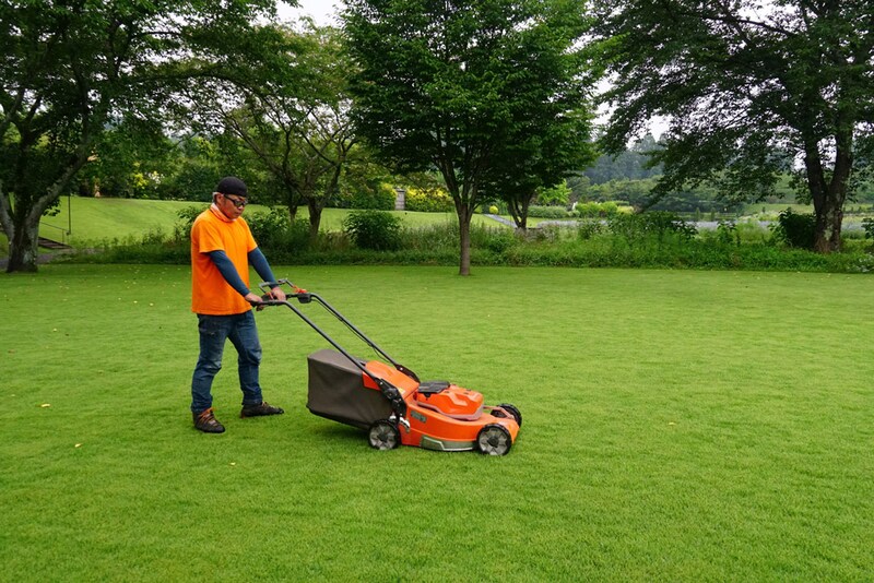芝生の手入れをする生須さん。