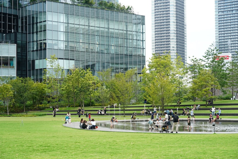 うめきた公園(南公園)。水盤で遊ぶ子どもたちや、アンフィローンに座って食事をする人たちが見られる。