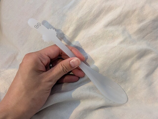 ニョロニョロデザインの白いスプーンを手に持ったサイズ感