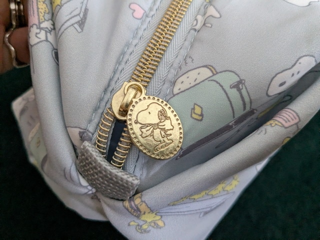 ゴールドの引き手にスヌーピー刻印のチャームが付いたディテール