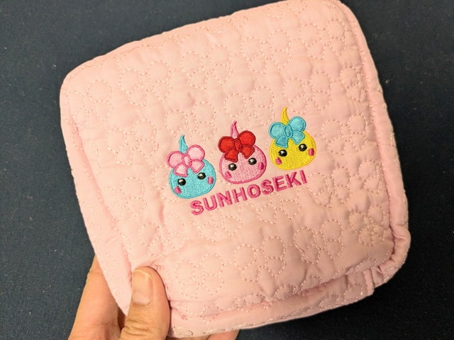 ほっぺちゃんキルティングポーチの正面。3キャラクターの刺繍とSUNHOSEKIロゴ