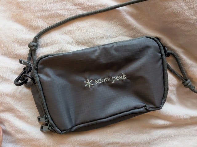 Snow Peakお財布ショルダーバッグの前面全体。ブラックのボディにスノーピークのロゴが刺繍されている