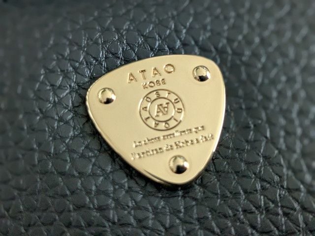 ATAOの三角プレートのアップ。ATAO KOBEの文字とロゴが刻まれたゴールドプレート