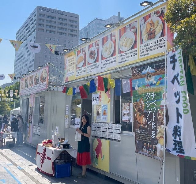 チベットレストラン＆カフェ タシデレのブース外観。カラフルな旗が飾られ、チベット料理のメニュー看板が並ぶ