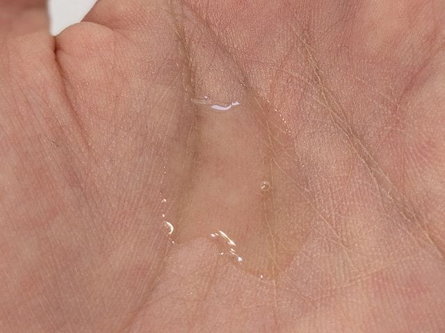 グローシンク ブーストセラムのテクスチャー。手のひらに透明でさらりとしたリキッドが伸びている