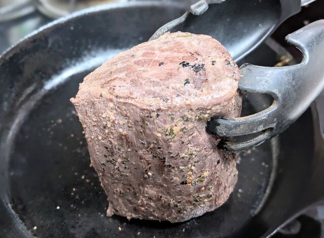 フライパンでトングを使いローストビーフを焼いている様子。外側に香ばしい焼き色がついた状態
