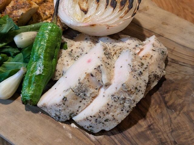 三宿ソルトチキンのカット断面。ハーブの香るやわらかなチキンにグリル野菜を添えたまな板の上の盛り付け
