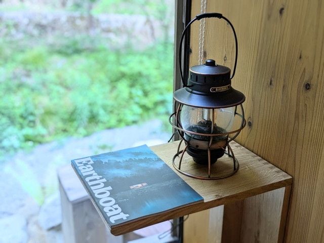 窓辺に置かれたランタンとEarthboatのブック