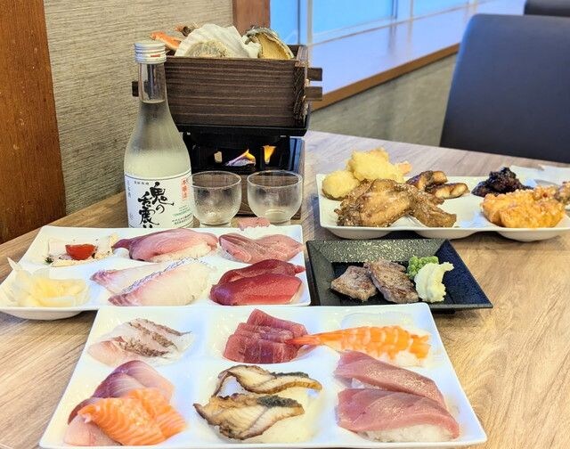 地酒のボトルとお造り、寿司、ステーキなどが並ぶ夕食の食卓全景