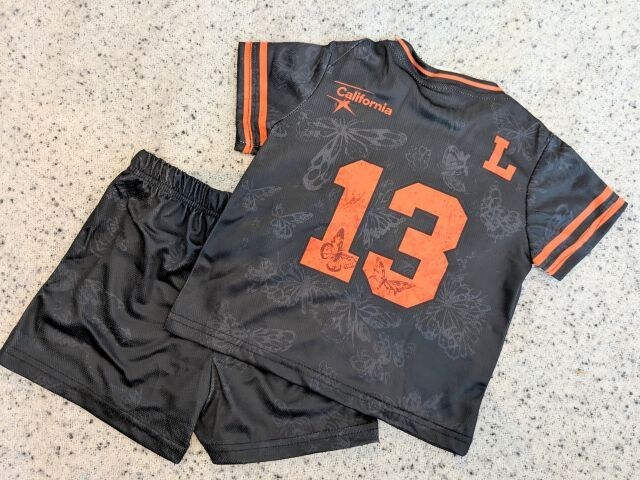 黒地にオレンジの「13」プリントが入ったスポーティーな半袖トップスとショートパンツのセットアップ（背面）