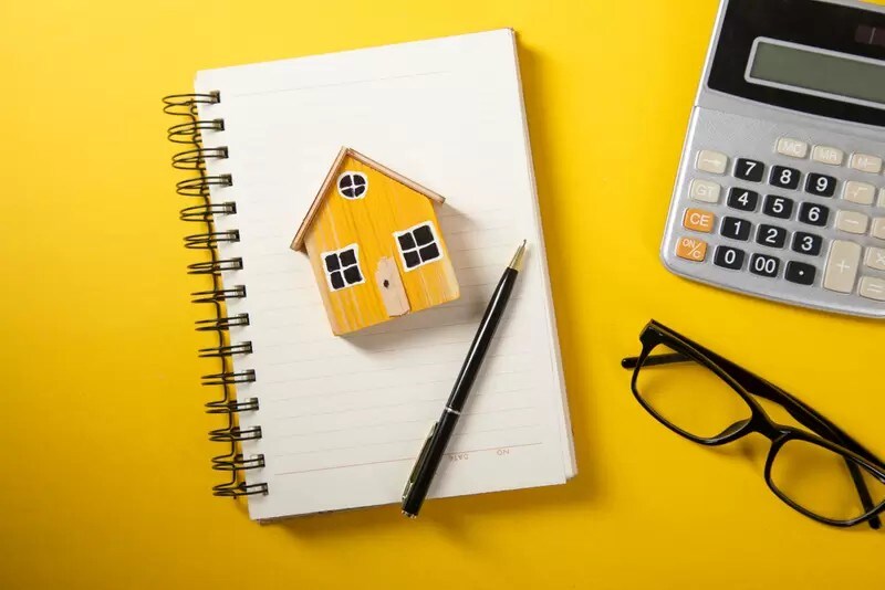 机の上のノートと電卓と家のモデル