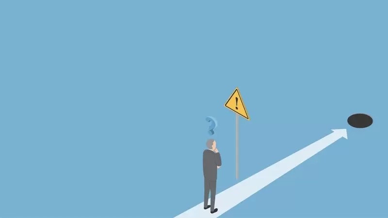 危険の標識を見て考えるシニア会社員男性と落とし穴