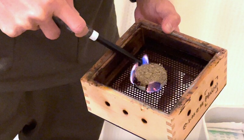 木箱の中に大きな灸を入れ着火する様子