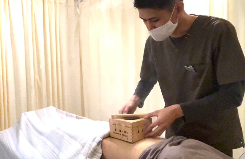 木箱をお腹の上に載せる久保さん