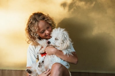 うっとりした表情で少女に抱かれる犬