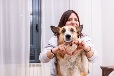犬とハートマークを作る女性