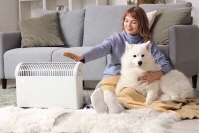 暖房で温まる犬と女性