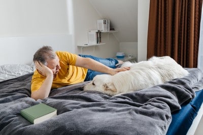 ベッドで愛犬を撫でている男性