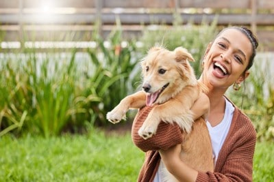 女性に抱っこされて笑っている犬
