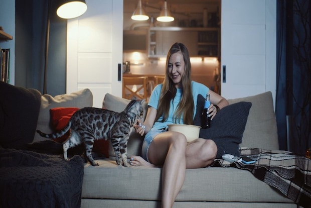 ソファで映画を見る女性と猫