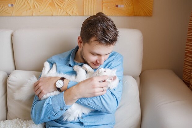 白い猫を抱く男性