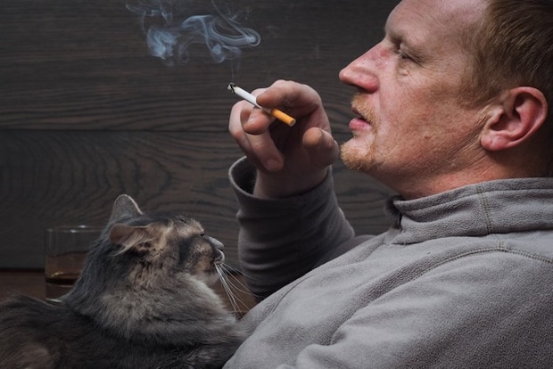 タバコを吸う男性と猫