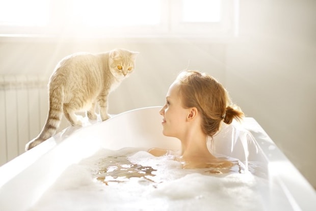 入浴する女性と浴槽の縁の猫