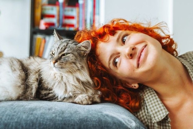 頭をくっつけ合う猫と女性