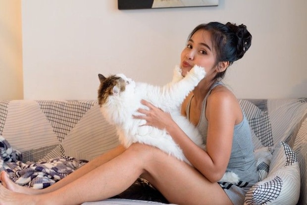 女性の顔に手を突っ張る猫