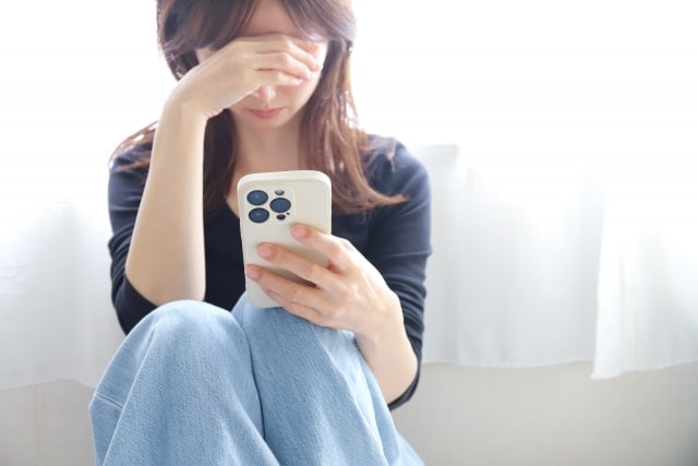 スマホを見て落ち込む女性