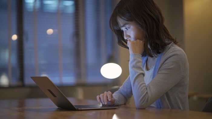 夜にパソコンで調べ物をする女性