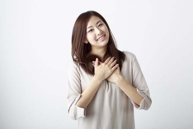胸のあたりに両手を当ててほほ笑む女性