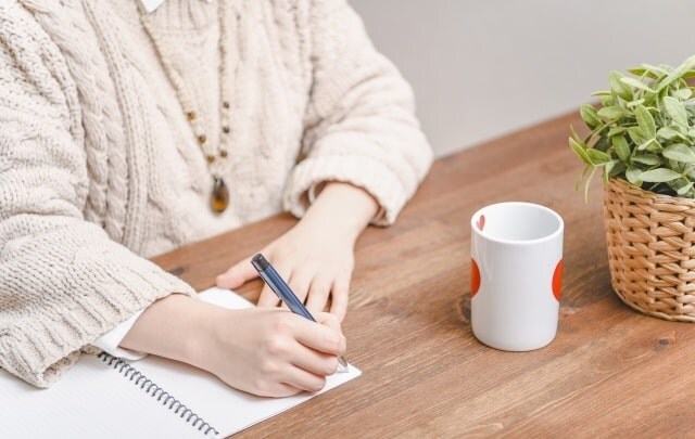 ノートに何かを書く女性