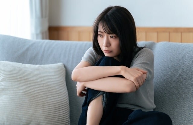 ソファの上で足をたてて何か考え事をしている女性