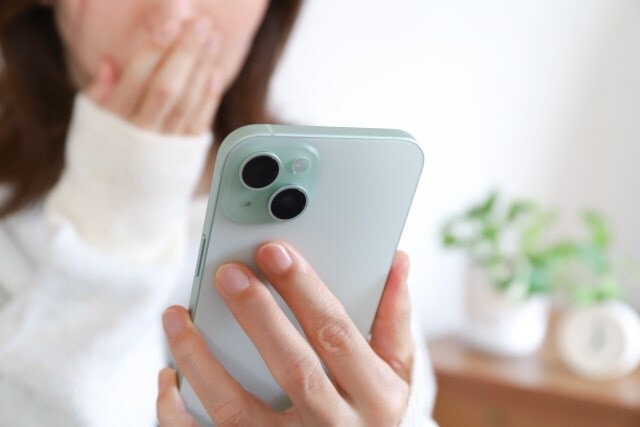 スマホを見て驚く女性の画像