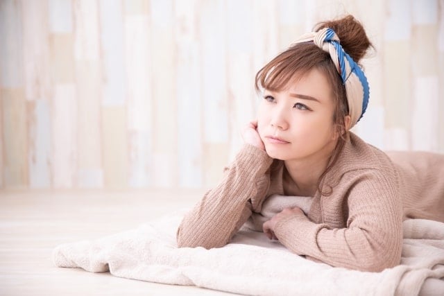 寝転んで疑問をもつ女性の画像