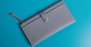 落ち着いたブルーのテーブルに置かれた灰色の合皮財布