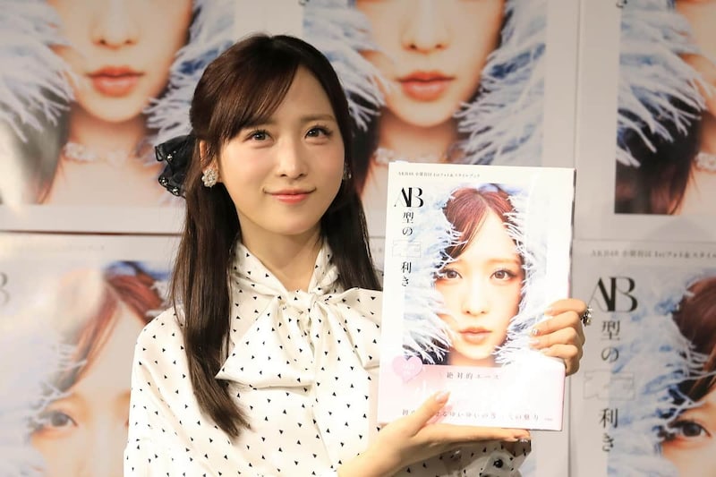 フォトブックを手に笑顔を見せる小栗有以さん