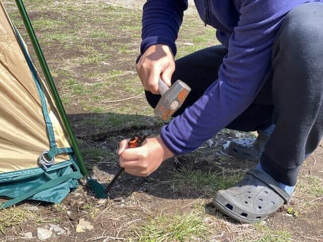 ペグを打ち付けテントを張る様子(画像はイメージ)