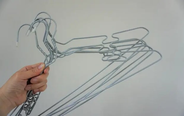 針金ハンガーを持つ人の手