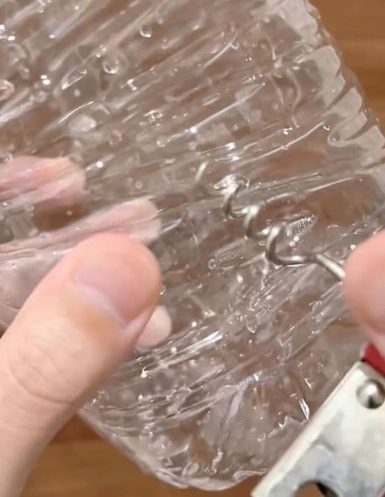 2ℓのペットボトルの下の方にコルク抜きで穴を開ける様子