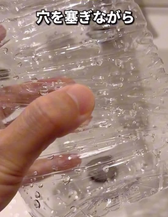 2ℓのペットボトルに開けた穴を指でふさぐ様子