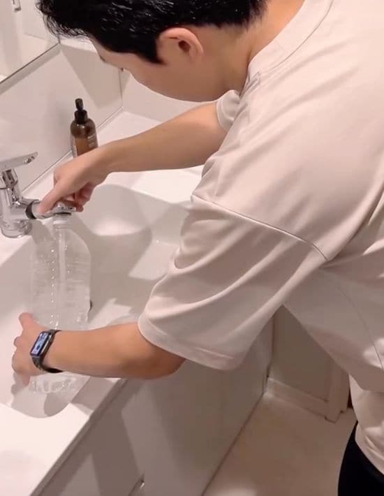 ペットボトルに開けた穴を指で押さえた状態で水を入れる様子