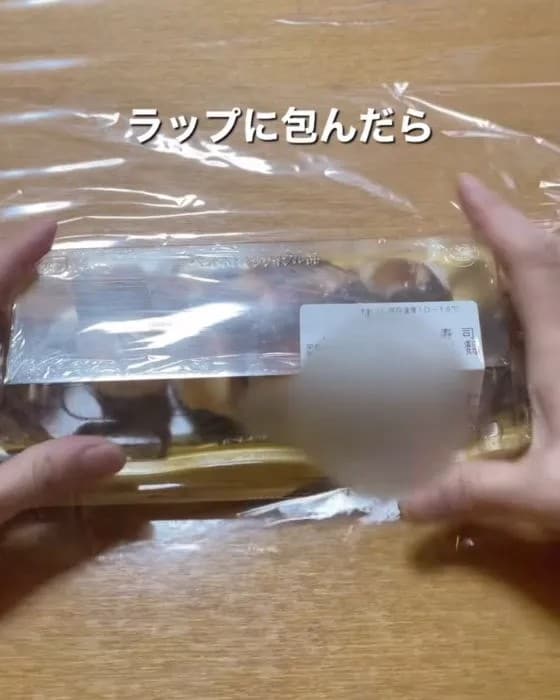 寿司のパックをラップで包んでいる様子