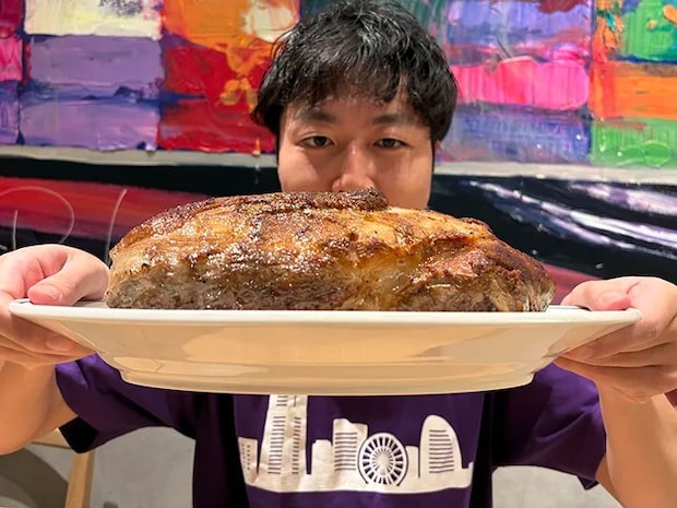 巨大なステーキを手にする男性の写真（撮影：grape編集部）