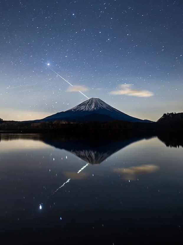 ふたご座流星群の流星が突き刺さったように見える富士山の写真
