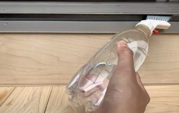 ペットボトルを使った掃除アイテムでサッシを掃除している様子