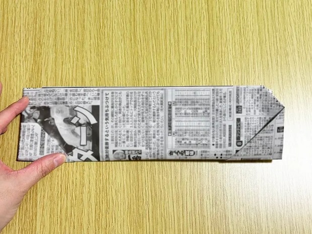 新聞紙で三角を折った後、半分に折った画像（撮影：grapeライフハック編集部）